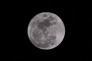The full moon, with its craters and other details visible, in the center of the frame