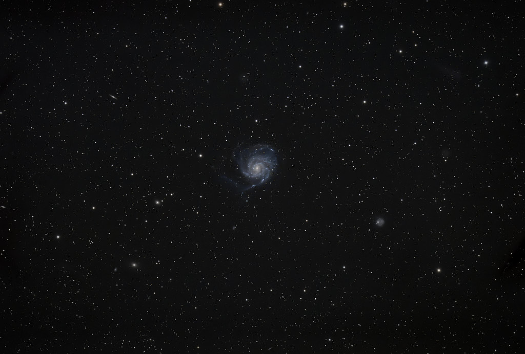 A spiral galaxy in the center of the frame, with a new bright star to the lower right of the center where a supernova has just taken place