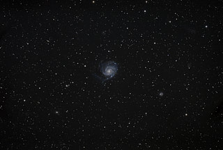A spiral galaxy in the center of the frame, with a new bright star to the lower right of the center where a supernova has just taken place