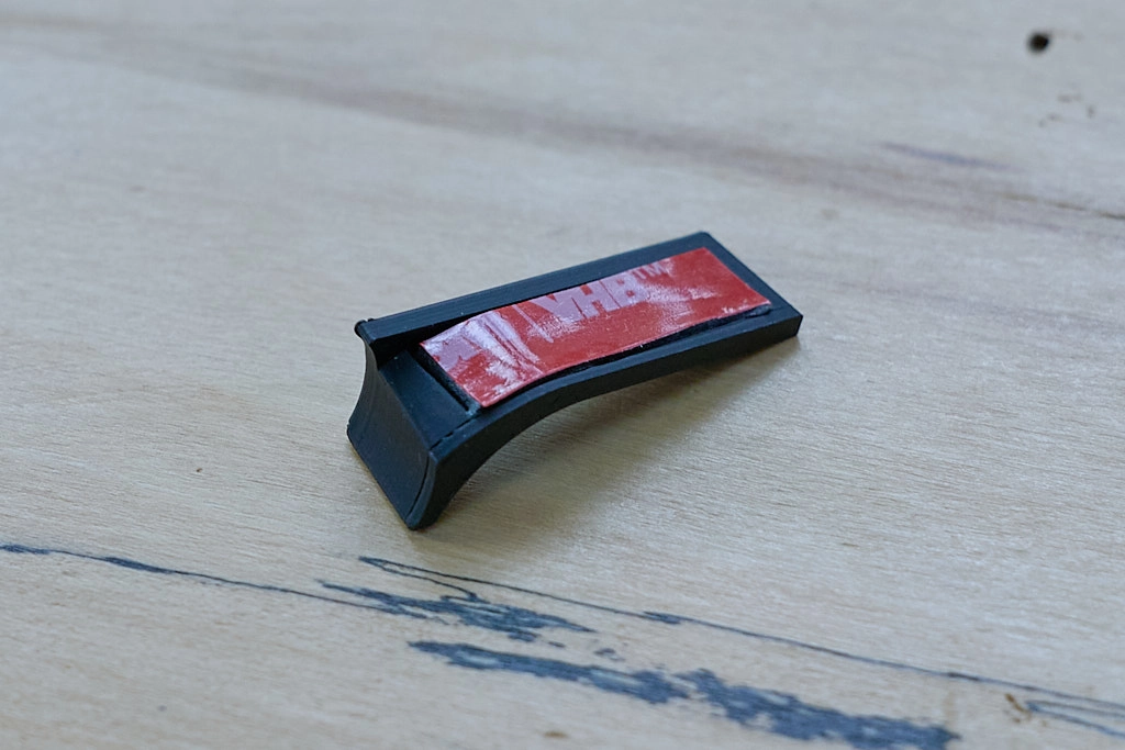 Photo of a thumb grip intended for a Leica M10 camera with VHB tabpe visible on the back