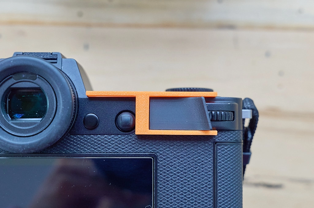 Photo of a mounting tool holding a thumb grip mounted to a Leica M10 camera in place