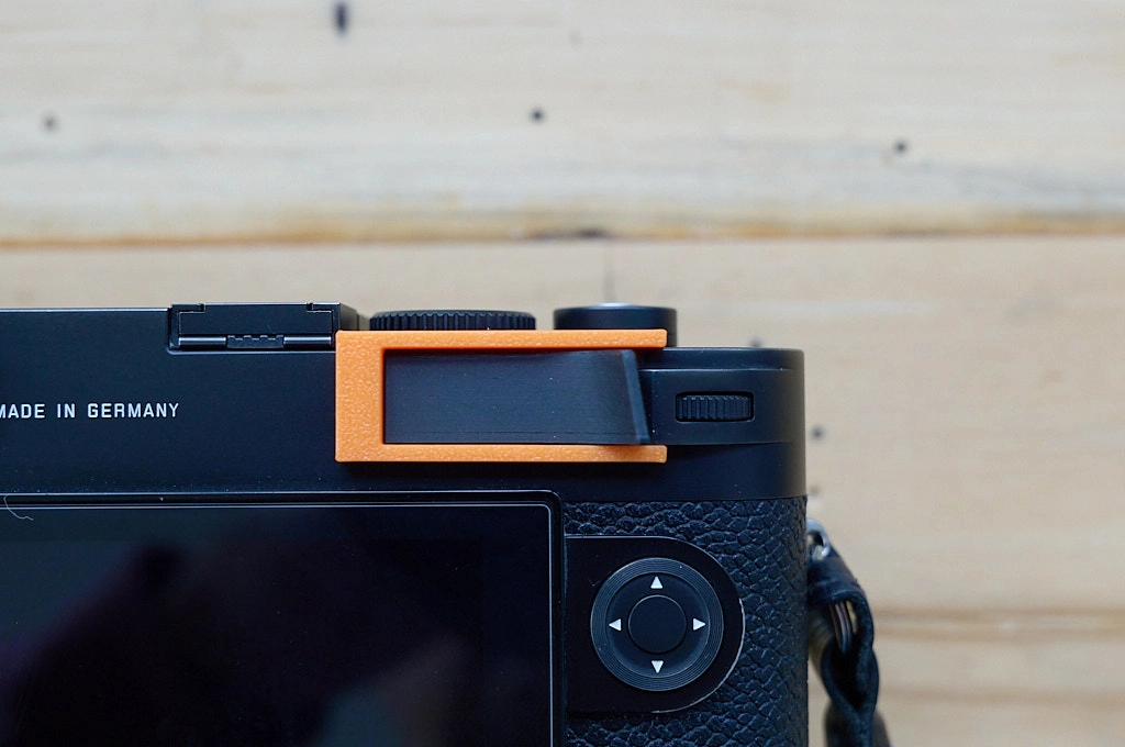 Photo of a mounting tool holding a thumb grip mounted to a Leica M10 camera in place